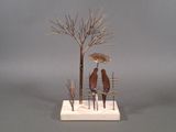 a sculpture of two people sitting on a bench under an umbrella