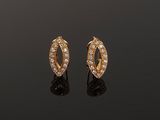 a pair of gold and diamond earrings on a black surface