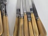 several forks and knives are lined up on a white surface