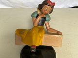 une petite figurine représentant une femme assise sur un banc