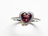 un gros plan d'une bague en forme de cœur sertie de diamants, sur fond blanc