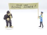 two figurines of a man and a gorilla holding a sign
