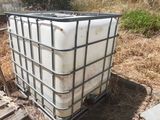 a large white container sitting on the ground next to a fence