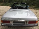 a silver convertible car parked on a gravel road