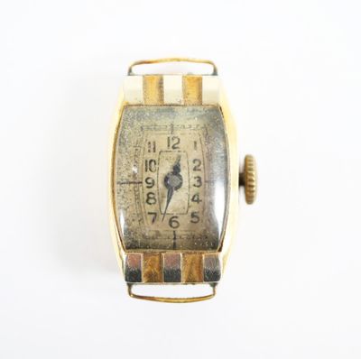 une montre en or avec un cadran blanc posée sur une surface blanche