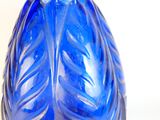 un vase en verre bleu orné d'un motif de feuilles