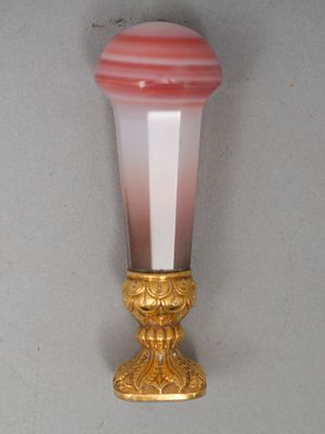 un vase rose et blanc avec un socle doré posé sur une table