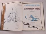 un livre ouvert sur lequel figure le dessin d'une femme et d'un dragon