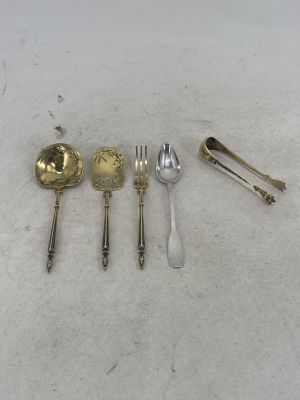 five silver spoons and two silver spoons on a white surface