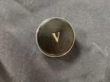 a close up of a black and gold lapel pin with a v on it