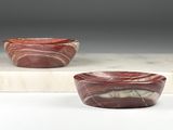 deux bols en marbre rouge posés sur une dalle de marbre