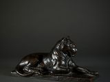 a bronze statue of a lion laying down on a black surface