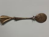 an old brass spoon with a metal handle on a white surface
