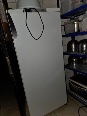 un réfrigérateur blanc dans une pièce où sont rangées des casseroles et des poêles sur des étagères