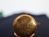 a close up of a gold pocket watch on a black cloth