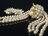 collier et boucles d'oreilles en perles sur un fond noir avec des reflets