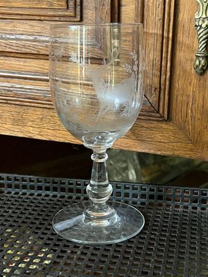 a glass of water sitting on a table with a wooden cabinet in the background