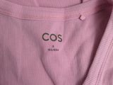 a close up of the back of a pink t shirt with the cos logo on it
