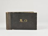 un livre noir orné de lettres dorées, posé sur une surface blanche