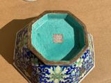 a blue and green vase sitting on a table next to a clock