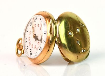 une montre de poche en or posée sur une surface blanche