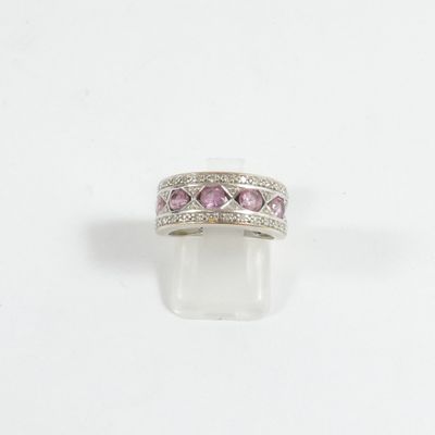 un gros plan d'une bague ornée de pierres roses sur fond blanc