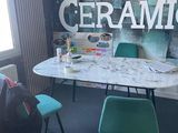 une table et des chaises dans une pièce où est accrochée une grande affiche au mur