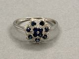 un gros plan d'une bague sertie de diamants et de saphirs posée sur une table