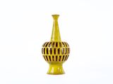 un vase jaune posé sur une surface blanche