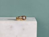 une image représentant une bague en or posée sur un bloc de marbre blanc