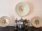 three silver plates and a silver teapot on a table