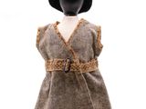 une poupée vêtue d'une robe marron et d'un chapeau noir, posée sur un mannequin