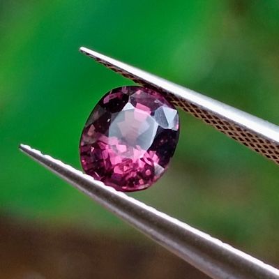 un gros plan d'un diamant rose tenu par une paire de pinces