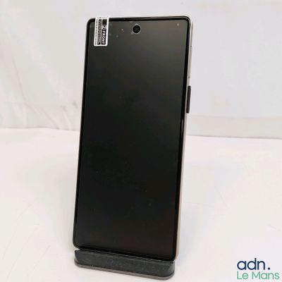 the back of a black cell phone sitting on top of a white table