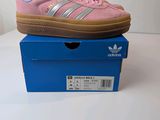 pink adidas sneakers on a blue box on a white surface