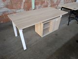 a desk with a cabinet and a chair in front of a brick wall