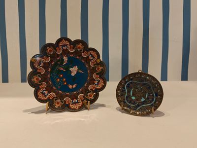 deux assiettes décoratives posées sur une table recouverte d'un papier peint à rayures bleues et blanches