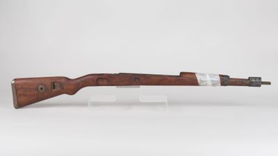 a rifle with a wooden barrel on a clear stand