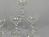 three clear glass goblets and two empty wine glasses on a table