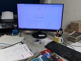 a desk with a computer, keyboard, mouse, and papers on it