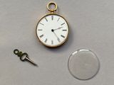 une montre de poche en or et une clé posées sur une table