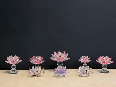 six vases en verre en forme de fleur de lotus posés sur une table devant un fond noir