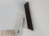a brush that is next to a ruler on a table