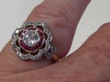 a woman ' s hand holding a diamond and ruby ring