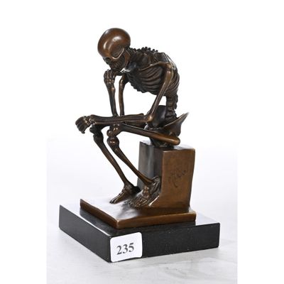 La statue d'un squelette est assise sur un bloc de bois.