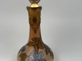a small glass bottle with a gold handle on a white surface