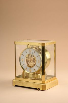 a small gold clock with a glass case on top of it