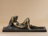 a bronze statue of a woman laying down on her stomach
