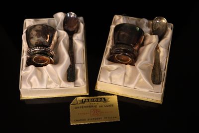two silver spoons and a silver cup in a box