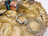 many different types of bracelets and rings on a tray